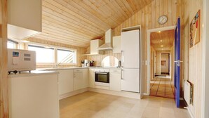 Una cucina moderna con rivestimenti in legno, forno integrato e frigorifero.