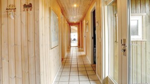 Un corridoio in legno con pavimento piastrellato che conduce a una porta con una finestra.