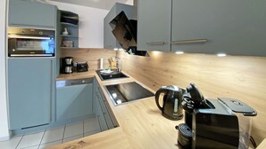 Une cuisine moderne avec des meubles gris, un four encastré, un évier et un plan de travail en bois.