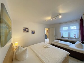 Quarto de hotel com duas camas, um quadro na parede e janela com cortinas.
