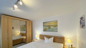 Une chambre d’hôtel avec un grand lit, une armoire en bois, des lampes de chevet et un tableau au mur.