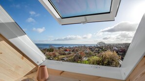 Ein Dachfenster mit Blick auf eine Küstenstadt.