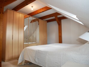 A bedroom with a bed, wooden wardrobe, and a skylight.
