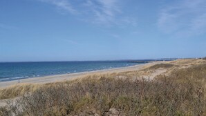A coastal landscape with a sandy beach, grassy dunes, and a clear blue sky. - 1 bedroom stunning apartment in Hornbæk (Hornbæk)