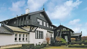 A two-story house with a steeply pitched roof, dormer windows, and a visible chimney. - 1 bedroom stunning apartment in Hornbæk (Hornbæk)