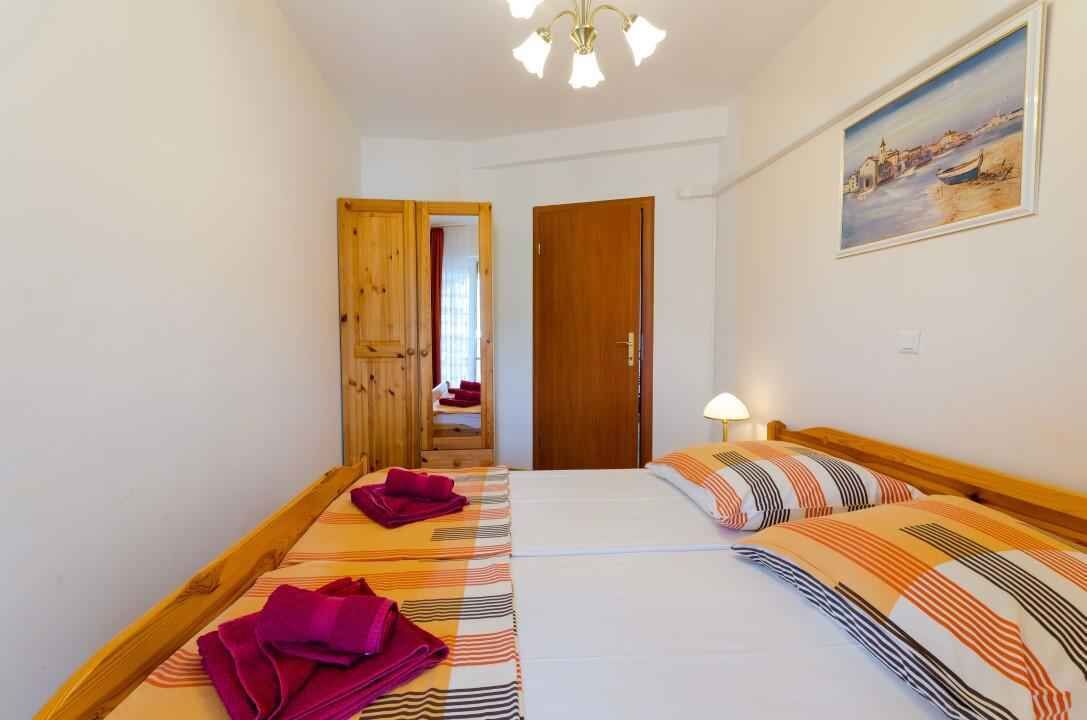 Une chambre d’hôtel avec deux lits, une porte en bois, un tableau au mur et un luminaire au plafond.
