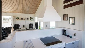 A modern kitchen with a built-in stove, a coffee maker, and a large window overlooking a scenic view. - Amazing home in Løkken with sauna (Løkken)