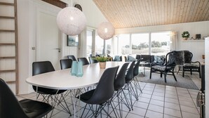 A modern dining area with a white table, black chairs, and two spherical pendant lights. - Amazing home in Løkken with sauna (Løkken)