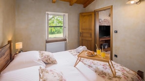 A bedroom with a bed, a window, a wooden door, a bedside table with a tray of croissants and orange juice, and a lamp. - Stunning home in Tinjan with sauna (Tinjan)
