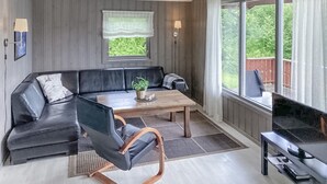 Un salon moderne avec un canapé d’angle, une table basse en bois et un meuble pour la télévision.