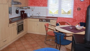 A compact kitchen with basic amenities, a dining area with a table and chairs, and a window with a view. - Sunshine house in Baabe - holiday home (Baabe)
