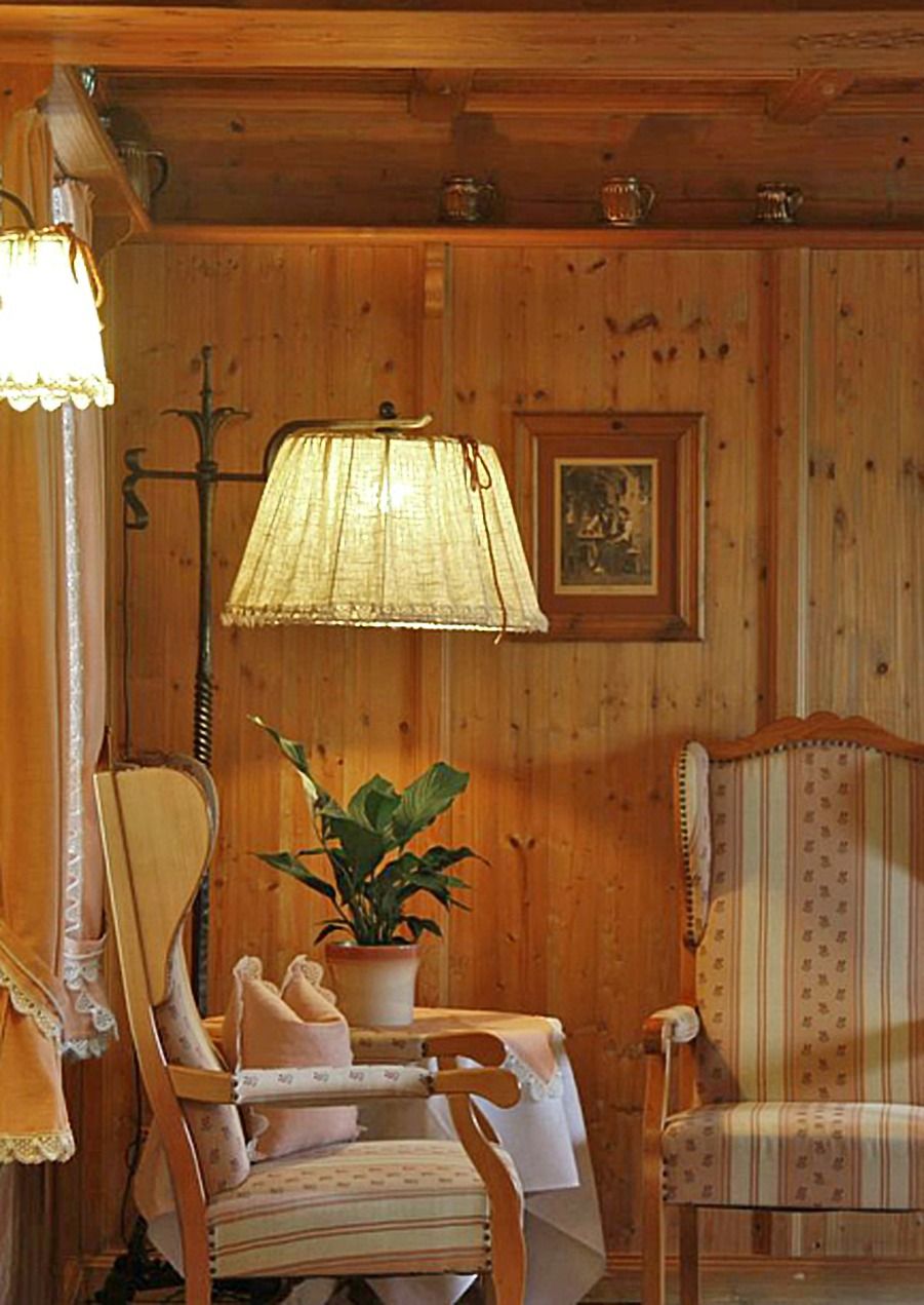 Une pièce aux murs lambrissés, avec une table, des chaises, une lampe et une plante en pot.