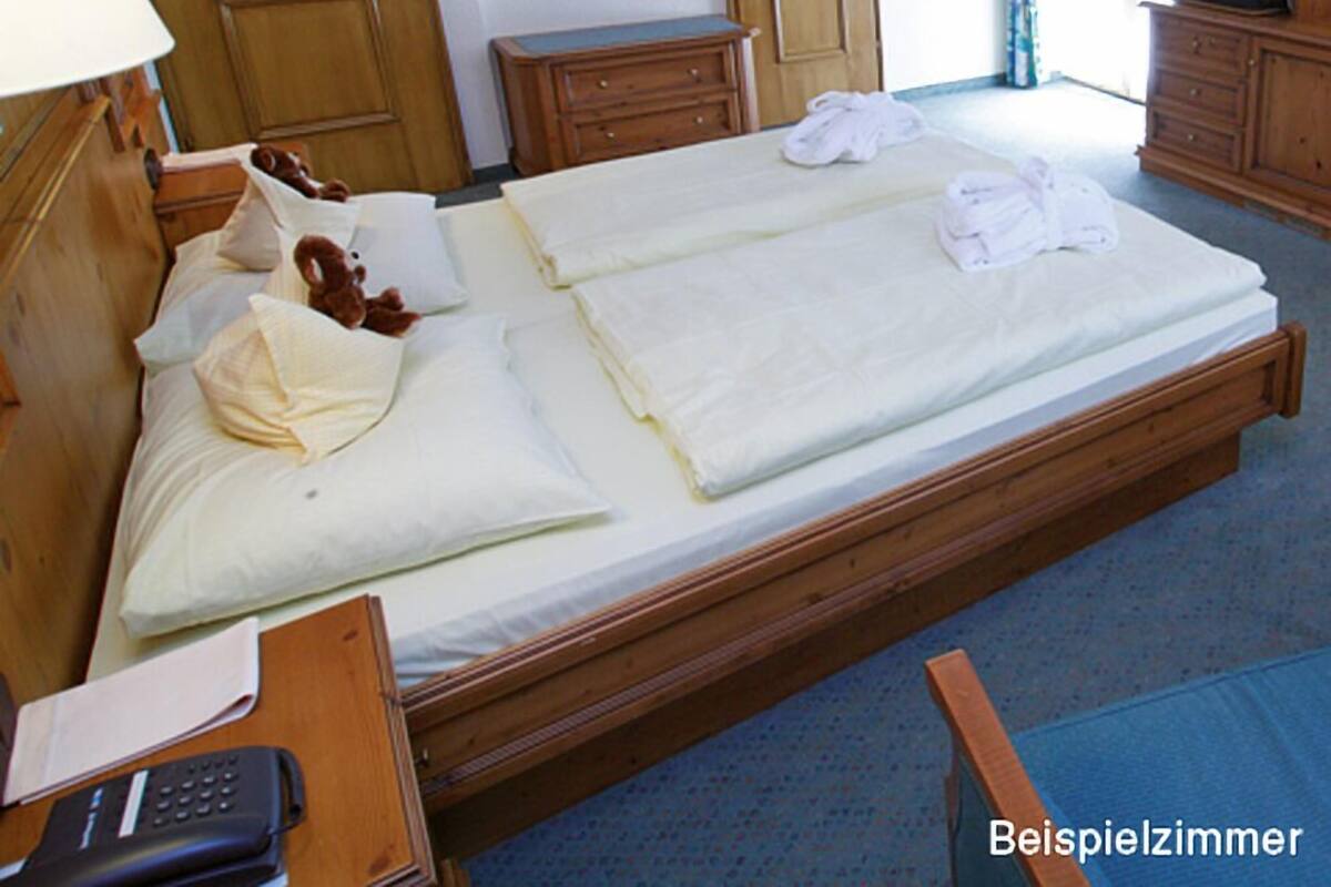 Una habitación de hotel con una cama grande, muebles de madera, un espejo y un televisor.