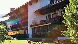 Un edificio su due piani con un balcone, posti a sedere all'aperto e un giardino.