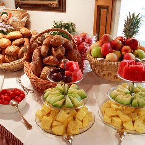 Uma mesa de buffet com diversos alimentos, incluindo pão, frutas e vegetais.