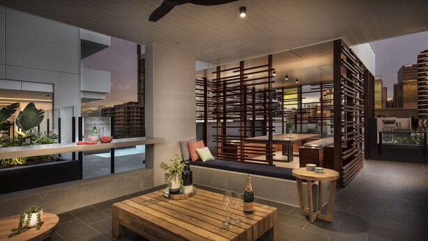 A modern lounge area with a wooden coffee table, seating, and a view of the cityscape. - Ivy and Eve Apartments by CLLIX (South Brisbane)