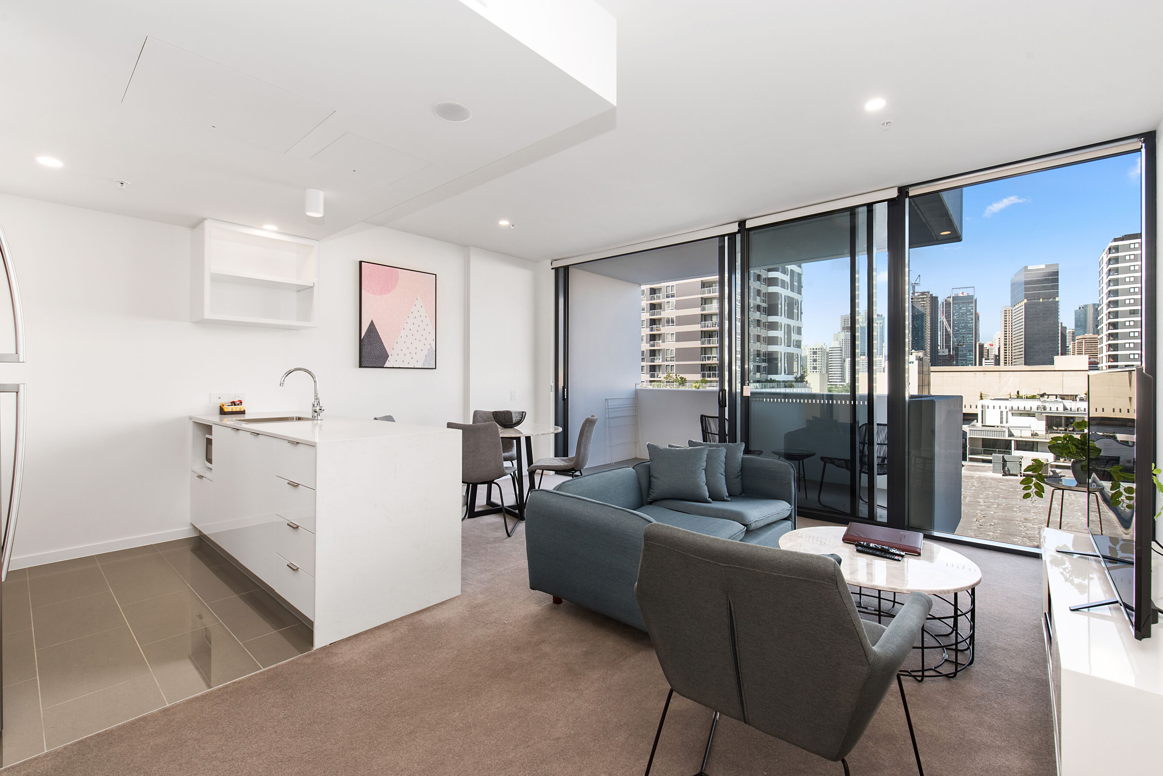 A modern apartment with a kitchen, living area, and large windows offering city views.