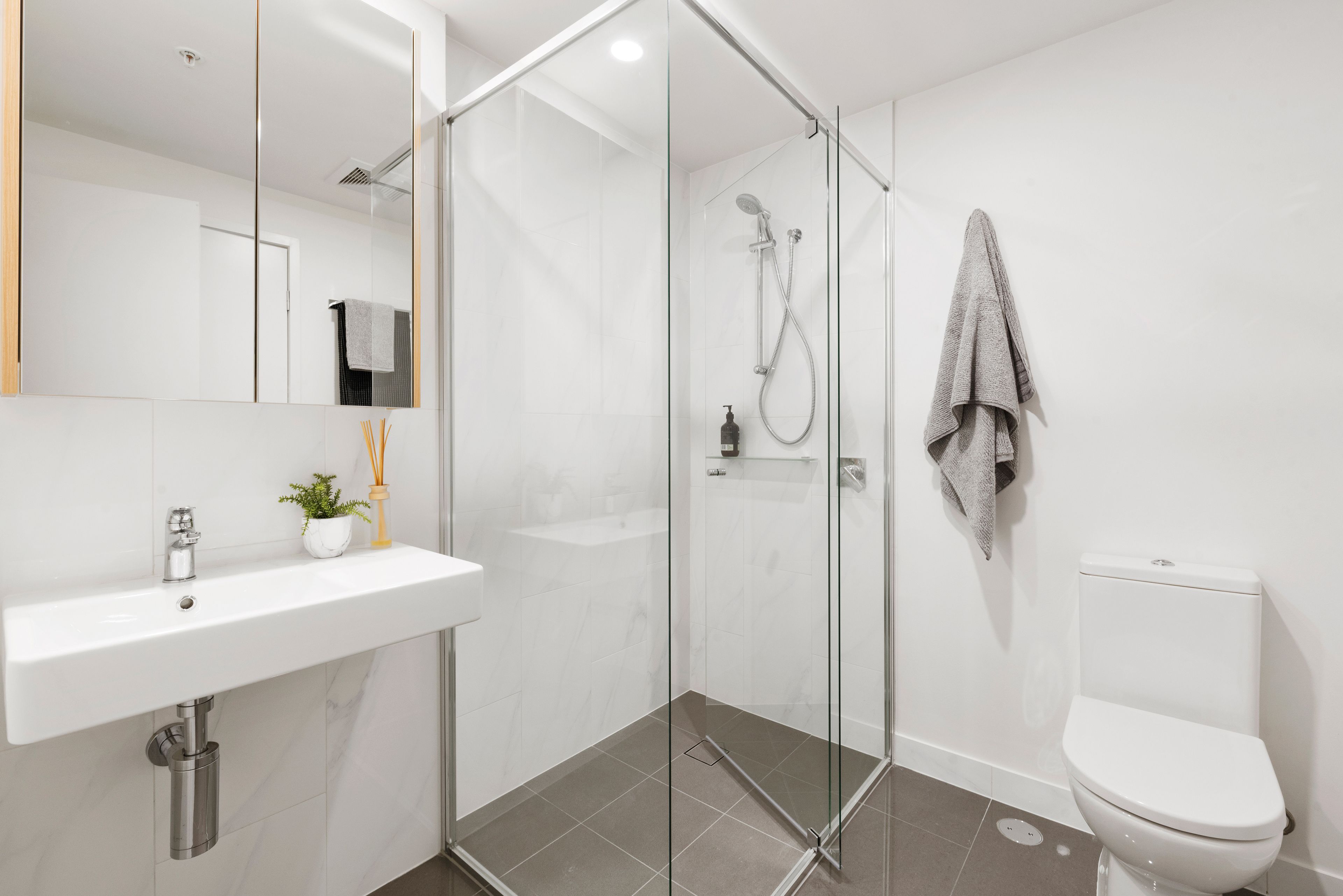 A modern bathroom with a glass-enclosed shower, a white sink, and a toilet.