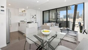 A modern apartment with a kitchen, dining area, and a large window with a city view. - Ivy and Eve Apartments by CLLIX (South Brisbane)