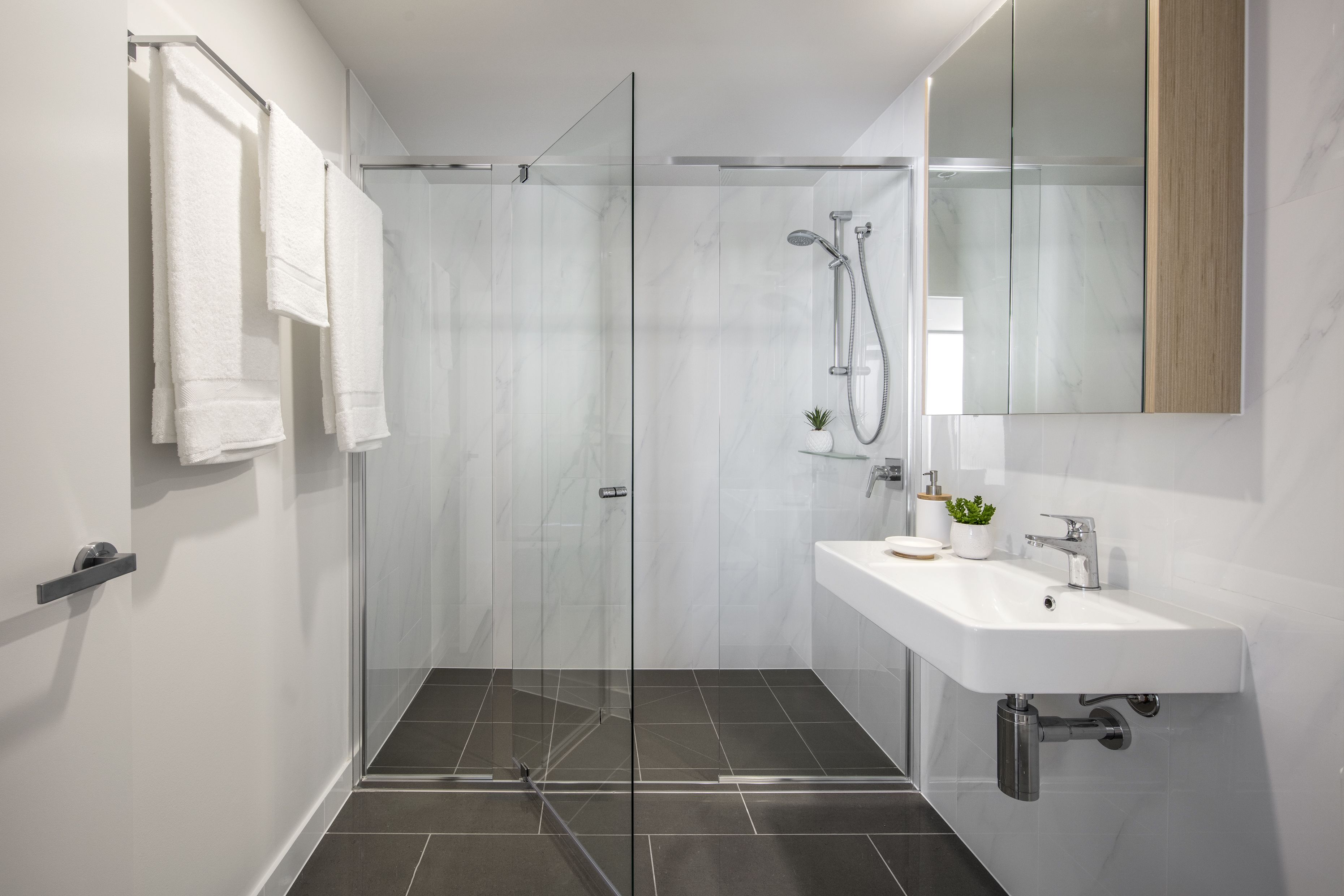 Un bagno moderno con doccia vetrata, lavandino bianco e uno specchio grande.