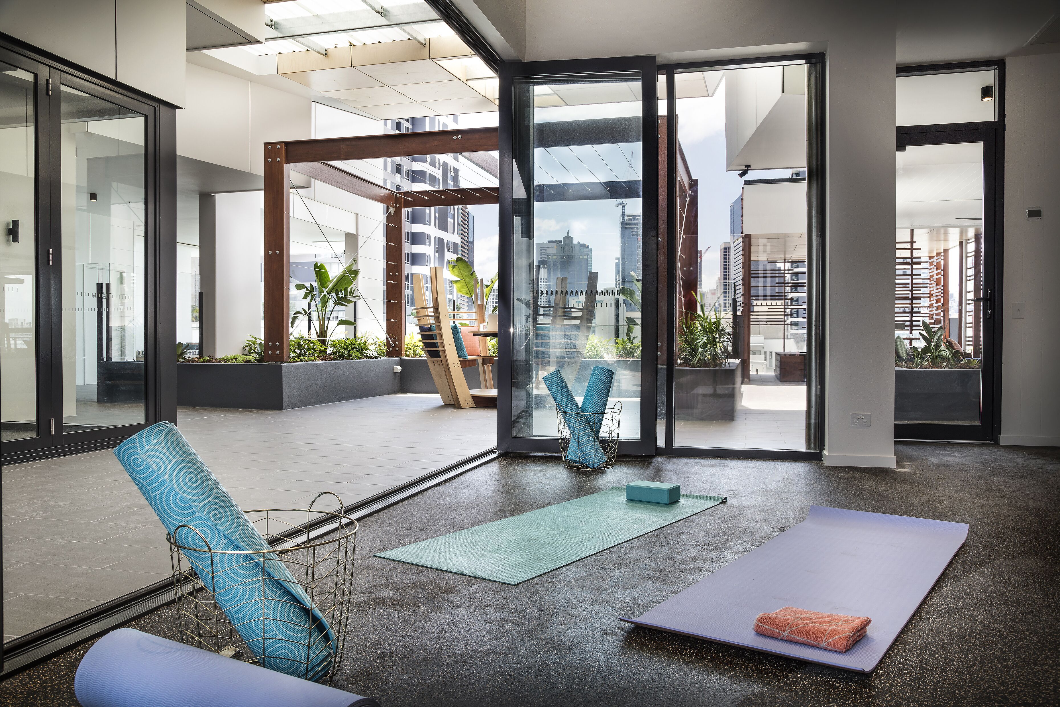 Un espacio de oficina con ventanas amplias, un tapete de yoga y una silla azul estampada.