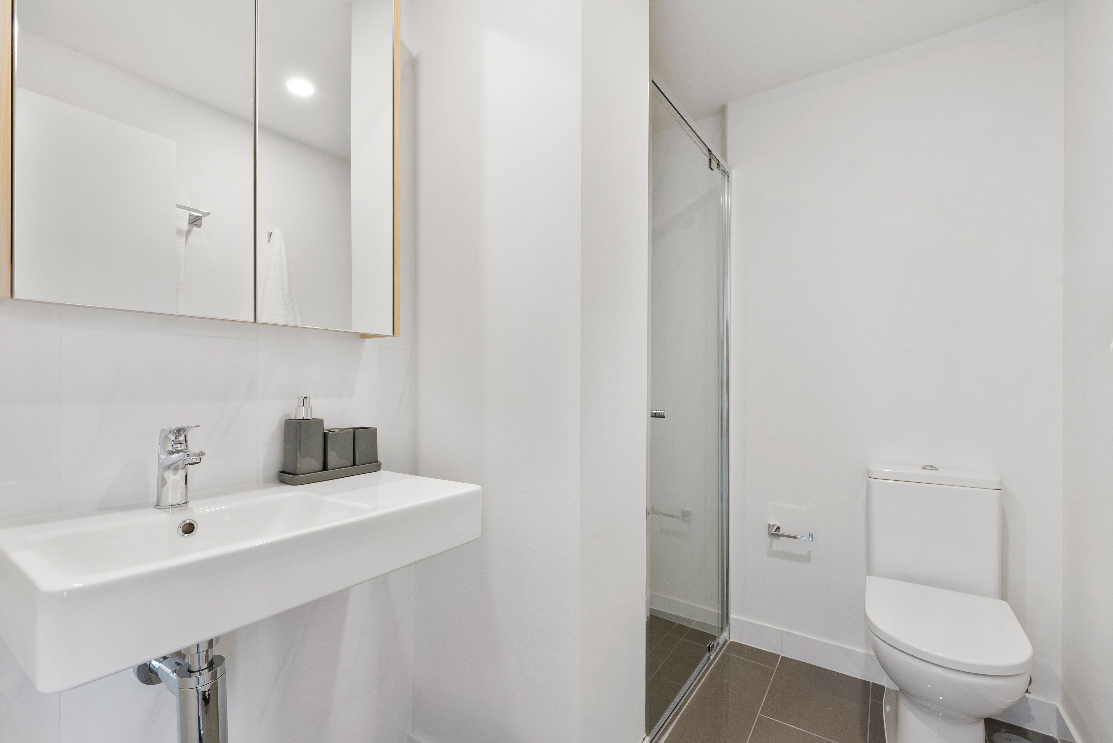Un bagno moderno con lavandino, specchio e water bianchi.