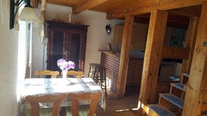 A rustic dining area with a wooden table and chairs, a vase of flowers, and a brick wall. - Holiday house Rankwitz - holiday house (Rankwitz)