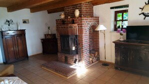 A living room with a brick fireplace, wooden furniture, and a television. - Holiday house Rankwitz - holiday house (Rankwitz)