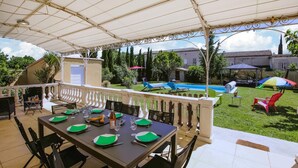 Eine Terrasse im Freien mit einem Esstisch, gedeckt für sechs Personen, umgeben von einer weißen Brüstung.
