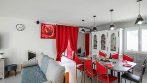 Eine moderne Küche mit roten und weißen Schränken, einem Esstisch mit roten Stühlen und einem großen Fenster mit Vorhängen.