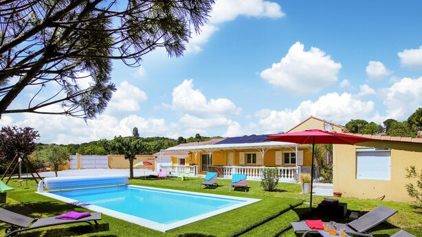 Ein Garten mit Schwimmbad, Liegestühlen und einem Haus mit Balkon.