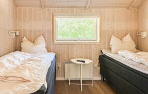 A room with two beds, a small table, a window, and a radiator. - Lovely home in Rømø with sauna (Rømø)