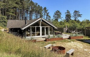 A modern cabin with a glass front, wooden deck, and a fire pit in the yard. - Lovely home in Rømø with sauna (Rømø)