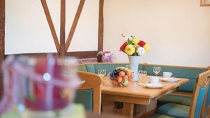 A dining area with a wooden table, a bowl of fruit, a vase of flowers, and green cushioned seating. - Stunning home in Burg Reuland/Steffesh. (Burg Reuland/Steffesh.)