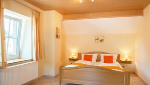 A bedroom with a wooden bed, two bedside tables with lamps, a window with curtains, and a radiator. - Stunning home in Burg Reuland/Steffesh. (Burg Reuland/Steffesh.)