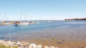 Un port de plaisance avec des bateaux amarrés le long de la côte, un ciel dégagé et un paysage rocheux au premier plan.