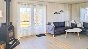 Un salon avec une cheminée, un canapé, une table basse et une vue dégagée grâce à de grandes fenêtres.