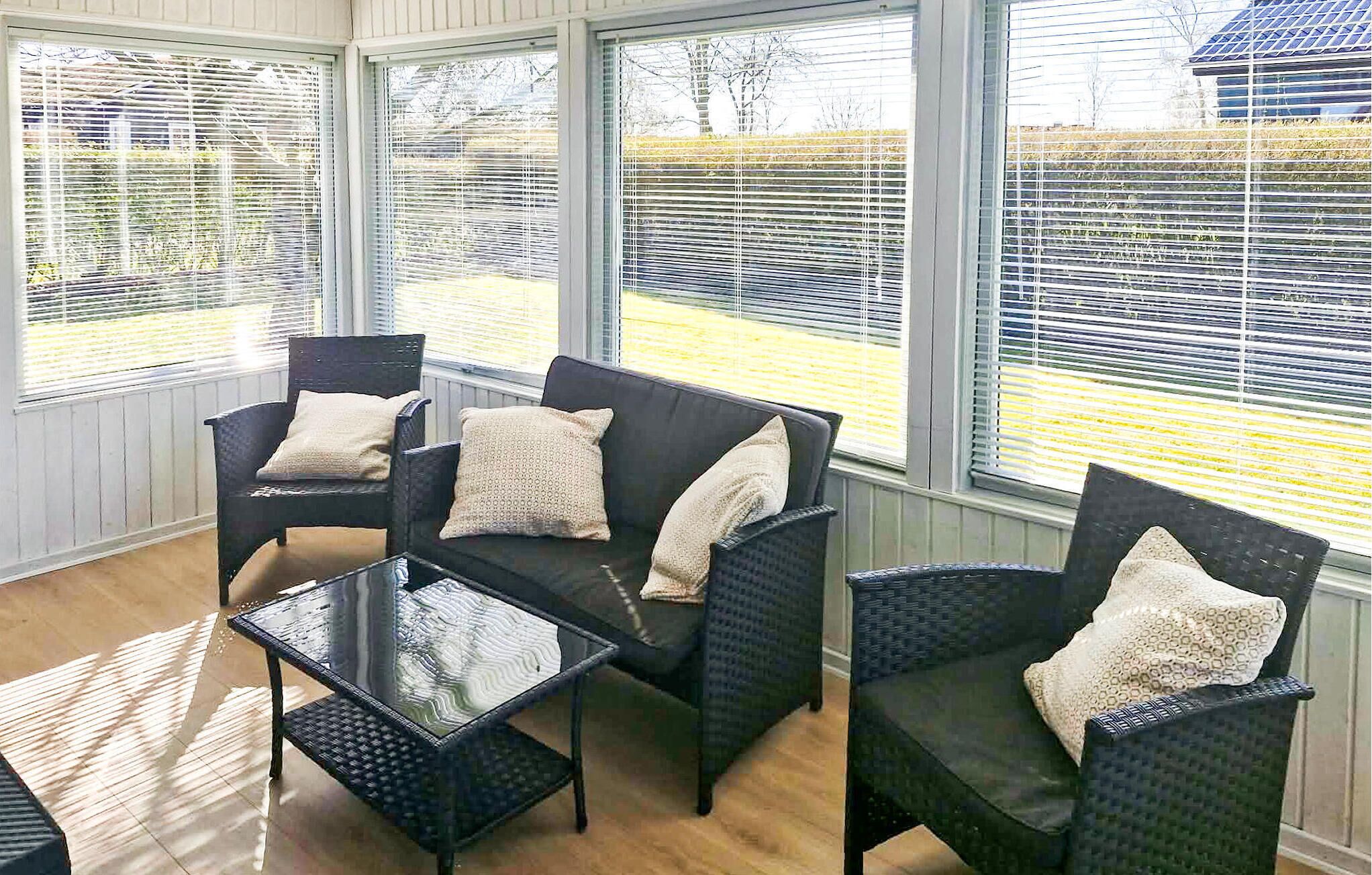 A sunroom with wicker furniture, large windows, and a view of a yard.