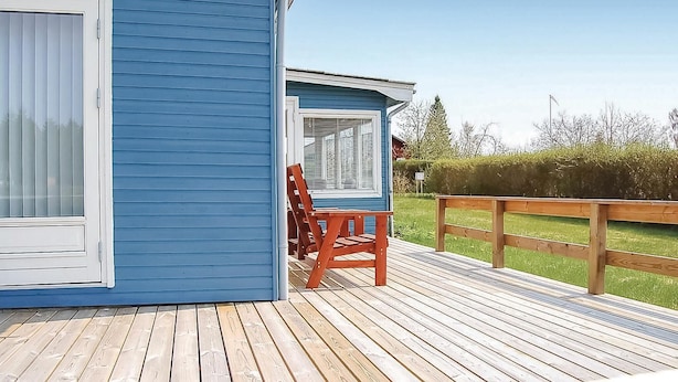 Un bâtiment bleu doté d’une terrasse en bois et d’une seule chaise en bois.