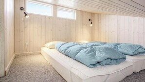 Une chambre à coucher avec un lit, deux fenêtres et un luminaire au plafond.