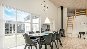 Un espace repas moderne, doté d’une grande table, de chaises et d’un écran de télévision.