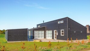 Un bâtiment moderne à deux étages, doté d’une façade sombre, de grandes fenêtres et d’une porte de garage bien visible.