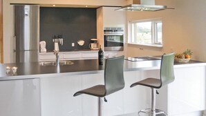 Et moderne køkken med en central ø, rustfrie hvidevarer og et vindue, der giver naturligt lys.