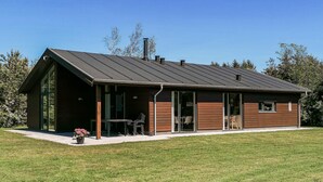 Et moderne, etetages hus med en stor veranda, et spiseområde og en garage.