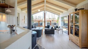 Ein großzügiger Wohnbereich mit hohen Decken, großen Fenstern und einer Holzkabine.