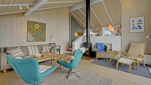 Tilava olohuone, jossa on korkea katto, takka ja modernit huonekalut.