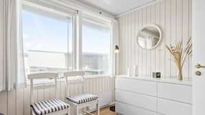 A modern, white-themed bathroom with a large window, two white chairs, a mirror, and a radiator. - Amazing home in Pandrup with WiFi (Pandrup)