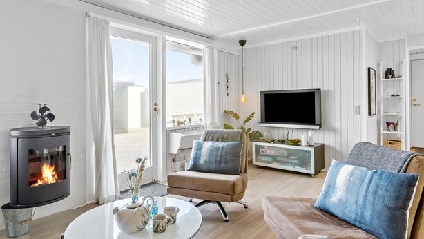 A modern living room with a fireplace, a television, and a cozy seating area. - Amazing home in Pandrup with WiFi (Pandrup)