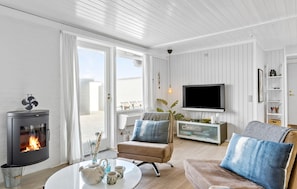 A modern living room with a fireplace, a television, and a cozy seating area. - Amazing home in Pandrup with WiFi (Pandrup)