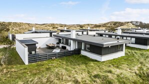 A modern residential complex with multiple two-story houses featuring flat roofs, large windows, and outdoor seating areas. - Amazing home in Pandrup with WiFi (Pandrup)